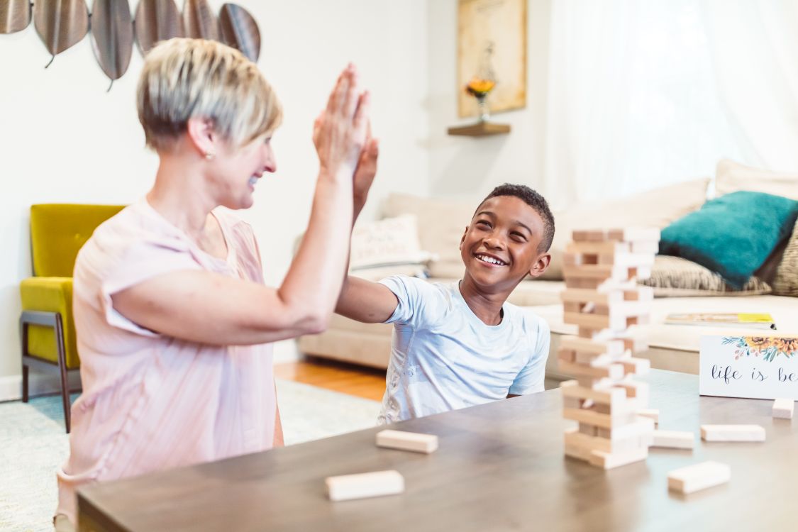 A smiling boy and his mother high-fiving while playing with building blocks