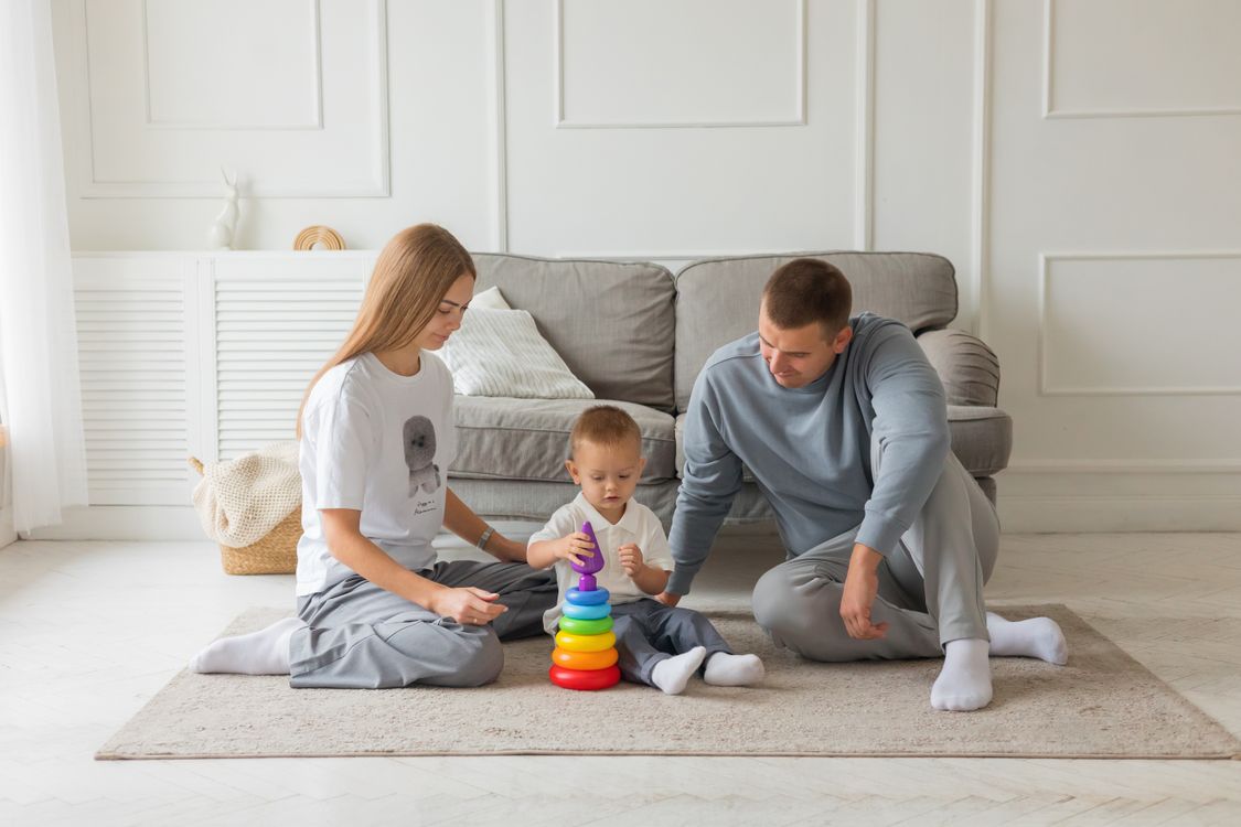 Parents playing with their young child and a colorful stacking toy