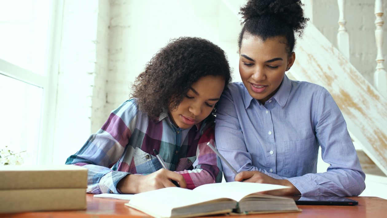A mother and daughter smiling as they study together at home